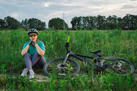 Woman Rests Beside Her Bicycle in a Fieldの写真素材