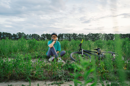 Woman Rests Beside Her Bicycle in a Fieldの写真素材