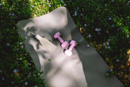 The items include a yoga mat, two dumbbells, a white water bottleの写真素材