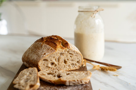 Freshly baked sourdough bread with a jar of starter and rustic clothの写真素材