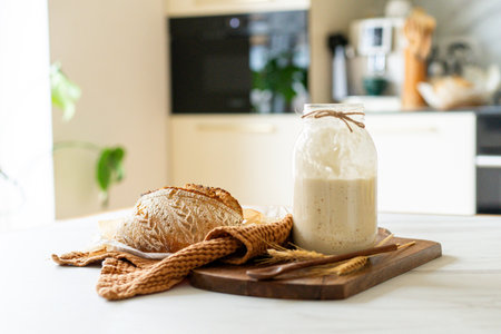 Freshly baked sourdough bread with a jar of starter and rustic clothの写真素材