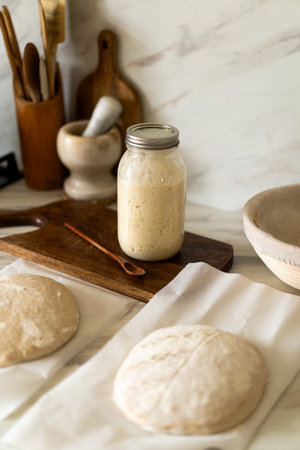 Baking sourdough bread in a cozy kitchen with fresh dough, starter preparationの写真素材