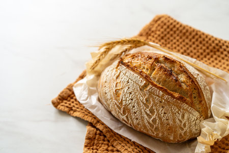 Freshly baked sourdough bread with a jar of starter and rustic clothの写真素材
