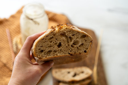 Freshly baked sourdough bread with a jar of starter and rustic clothの写真素材