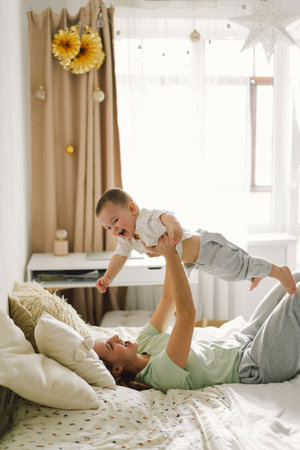 Home portrait of a baby boy with mother on the bed relaxing and playing