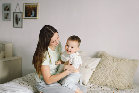 Home portrait of a baby boy with mother on the bed relaxing and playing