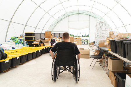 A veteran disabled man in a wheelchair helps in a humanitarian unit. Support of war victims.