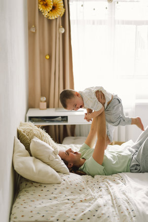 Home portrait of a baby boy with mother on the bed relaxing and playing