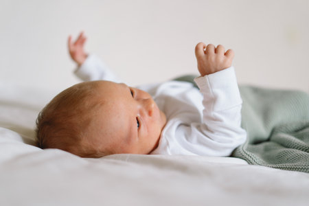 A newborn baby rests on a bed, wrapped in a soft blanket.