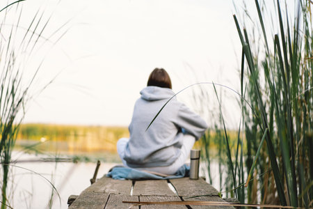 Woman traveler on a near the river, drinks a hot drink from a thermos