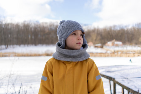 Child having fun in the snow, wearing winter clothing in snowy landscape during daytime.