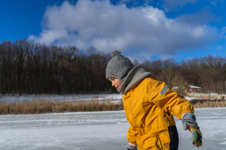 Child having fun in the snow, wearing winter clothing in snowy landscape during daytime.の写真素材