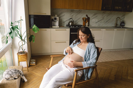 Pregnant woman gently holding her pregnant belly, reflecting on impending motherhoodの写真素材