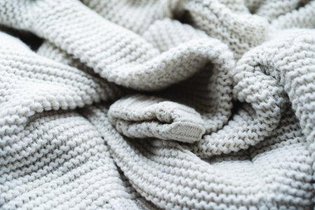 Soft textured gray blanket arranged in cozy folds on a neutral background for a warm atmosphere in a...