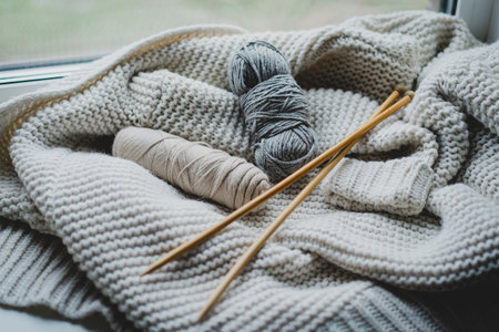 Knitting materials and soft yarn on a cozy blanket in a warm indoor settingの写真素材