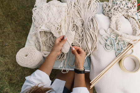 Woman knits bag using macrame technique outdoors near tents. Outdoor hobbies.の写真素材