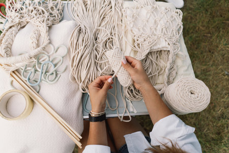 Woman knits bag using macrame technique outdoors near tents. Outdoor hobbies.の写真素材