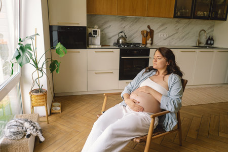 Pregnant woman gently holding her pregnant belly, reflecting on impending motherhoodの写真素材