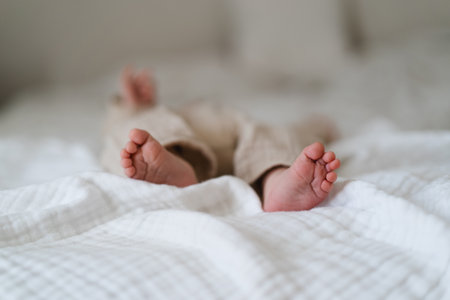 Baby feet wrapped in a cozy blanket on a soft bedの写真素材