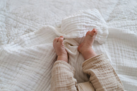 Baby feet wrapped in a cozy blanket on a soft bedの写真素材