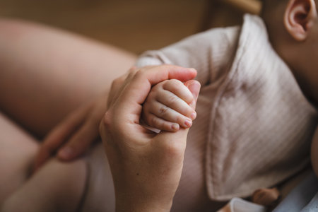 Woman comfortably breastfeeding her baby in a cozy roomの写真素材