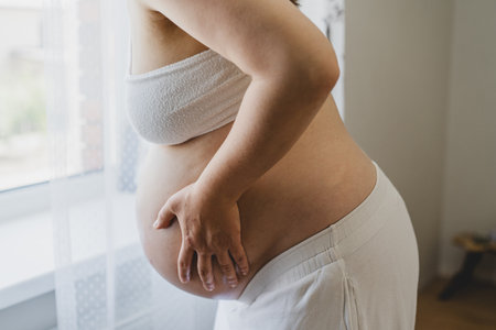 Pregnant woman in her third trimester holding her bellyの写真素材