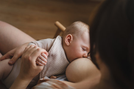 Woman comfortably breastfeeding her baby in a cozy roomの写真素材