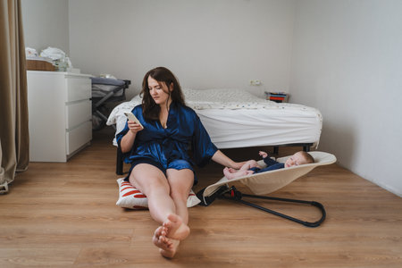 Mother relaxes on the floor with baby nearby in cozy room during calm morning hoursの写真素材