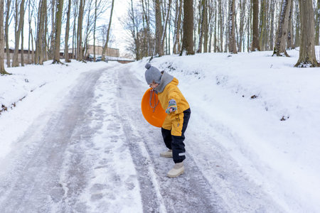 Child having fun in the snow, wearing winter clothing in snowy landscape during daytime.の写真素材
