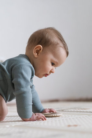 Baby lying on tummy on a soft play mat and playing with a sensory toy