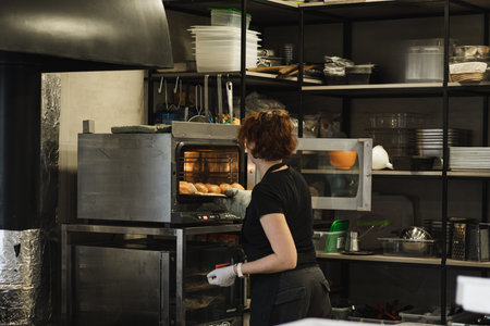 Smiling Female Baker Holding Fresh Artisan Sourdough Bread in Bakery