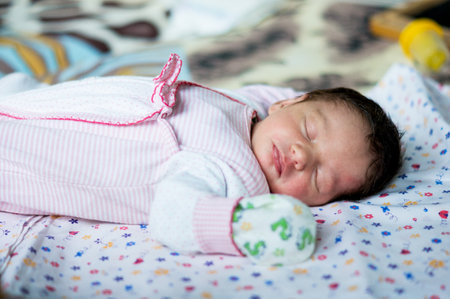 Little child or girl or baby or toddler or newborn sleeping on bed. Portrait of child. Newborn baby with dark or black hairの写真素材