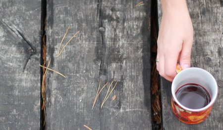 Cup of mulled wine in his hand on a table made of woodの写真素材
