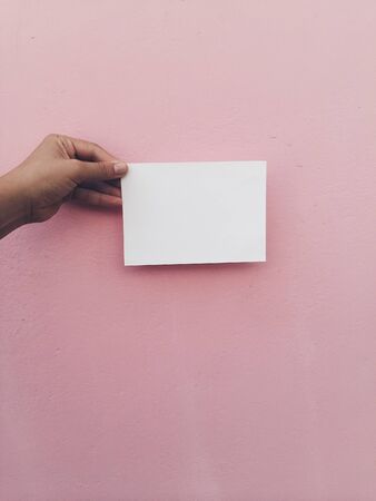 Hand hold white card at pink wall background