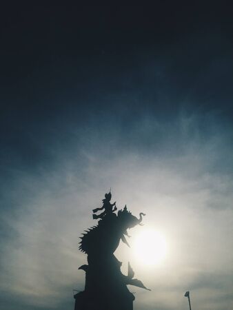 Silhouette of Indonesian statue at blue sky at background at sunsetの写真素材