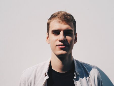 Young handsome stylish blonde guy at white wall at backgroundの写真素材