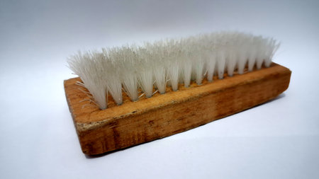 Compact wooden cleaning brush with durable white bristles isolated on a plain white surface,...