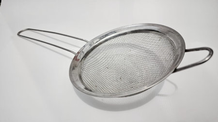 Stainless steel mesh strainer with handle, close up of kitchen sieve on white, essential cooking...