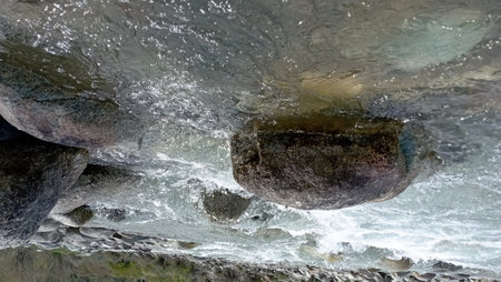 Mountain river flowing among rocks showcasing power and beauty of nature River rushes with crystal-clear water carving its path through stones Mesmerizing scene of river surrounded by rugged terrainの写真素材