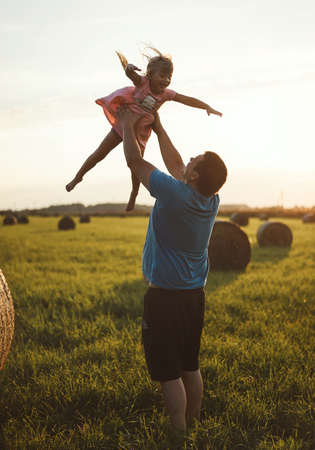 A happy child runs through a field of haystacks at sunsetの写真素材