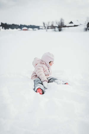 A small child plays snow games in nature in winterの写真素材