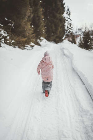 A small child plays snow games in nature in winterの写真素材