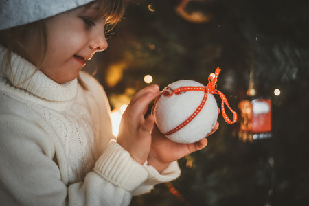 a small child plays with a Christmas tree and a Christmas tree toy in the new year at home with his familyの写真素材