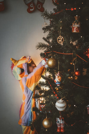 a small child plays with a Christmas tree and a Christmas tree toy in the new year at home with his familyの写真素材