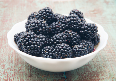 Blackberries in a bowl on wooden tableの写真素材