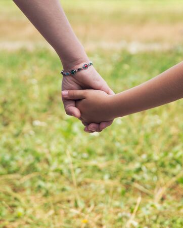 Mother holding a hand of his son in summer day outdoorsの写真素材