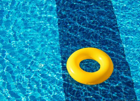 Yellow pool float, ring floating in a refreshing blue swimming poolの写真素材