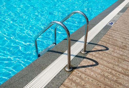 Grab bars ladder in the blue swimming pool