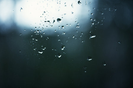 Water Droplets on a Pane of Glass with Blurred Garden Background. Close up of Raindrops on a Window.の写真素材