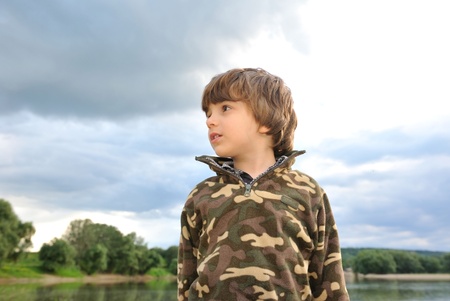 Portrait of a little boy on a background of the sky with clouds の写真素材